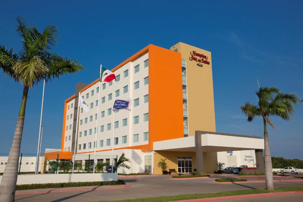 a hotel building with palm trees in front of it at Hampton Inn & Suites by Hilton Paraiso in Paraíso
