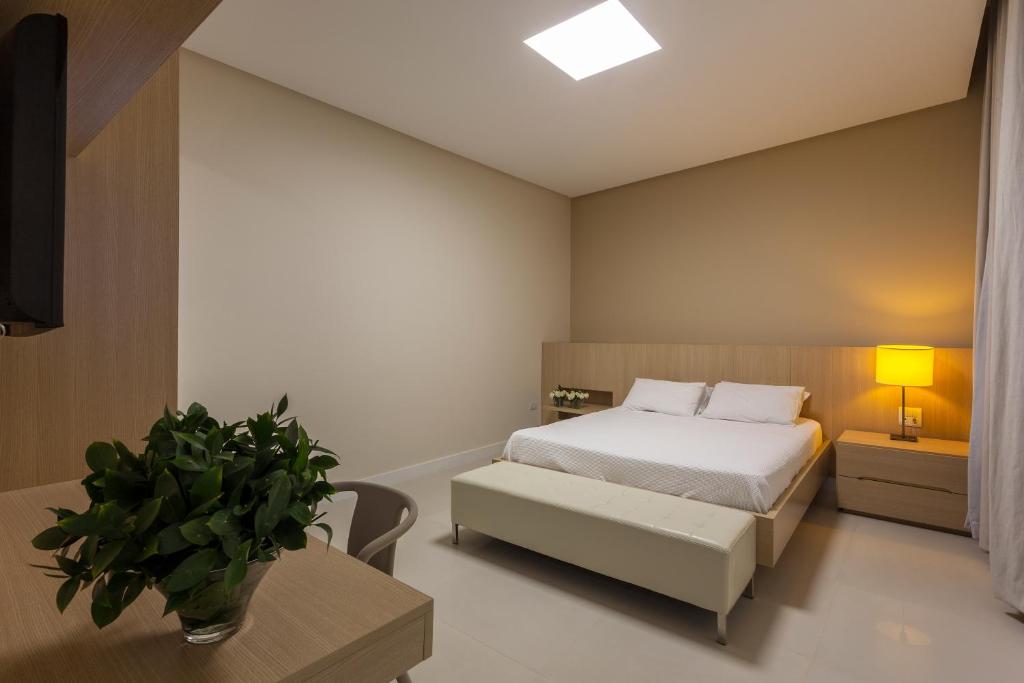 ein Schlafzimmer mit einem Bett und einem Tisch mit einer Topfpflanze in der Unterkunft Leopoldo Hotel in Guanambi