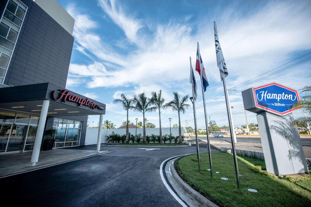 ein Hotel mit Flaggen vor einem Gebäude in der Unterkunft Hampton By Hilton Santo Domingo Airport in Boca Chica