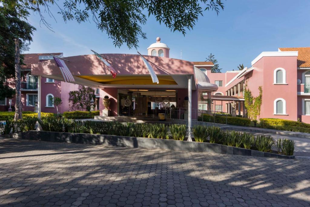 um edifício cor-de-rosa com um pavilhão à sua frente em Hilton MM Grand Hotel Puebla, Tapestry Collection em Puebla