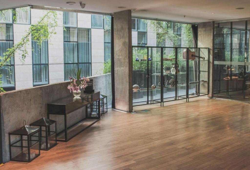 eine große Lobby mit Holzboden und Glasfenstern in der Unterkunft Anselmo Buenos Aires, Curio Collection by Hilton in Buenos Aires
