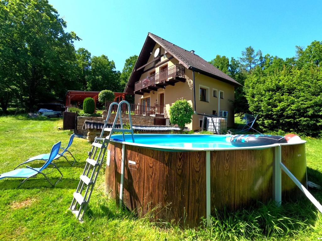 una piscina con una escalera junto a una casa en Chata Vikinka - dovolená v přírodě, 