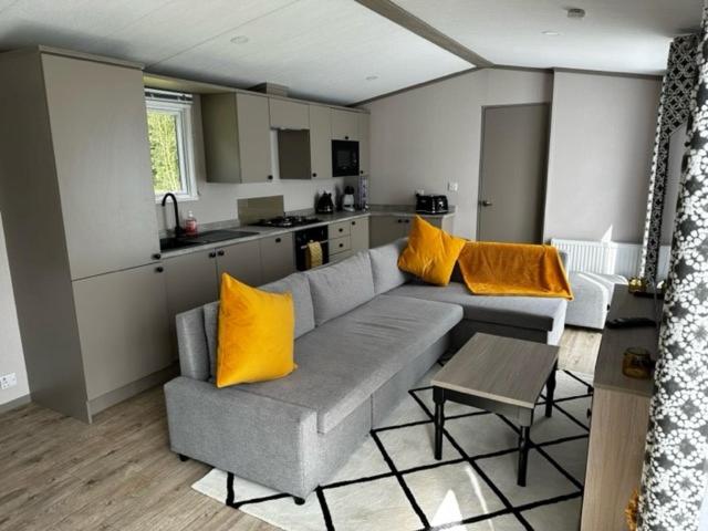 a living room with a gray couch and yellow pillows at Fairway 6 Lilliardsedge Caravan Hire in Jedburgh