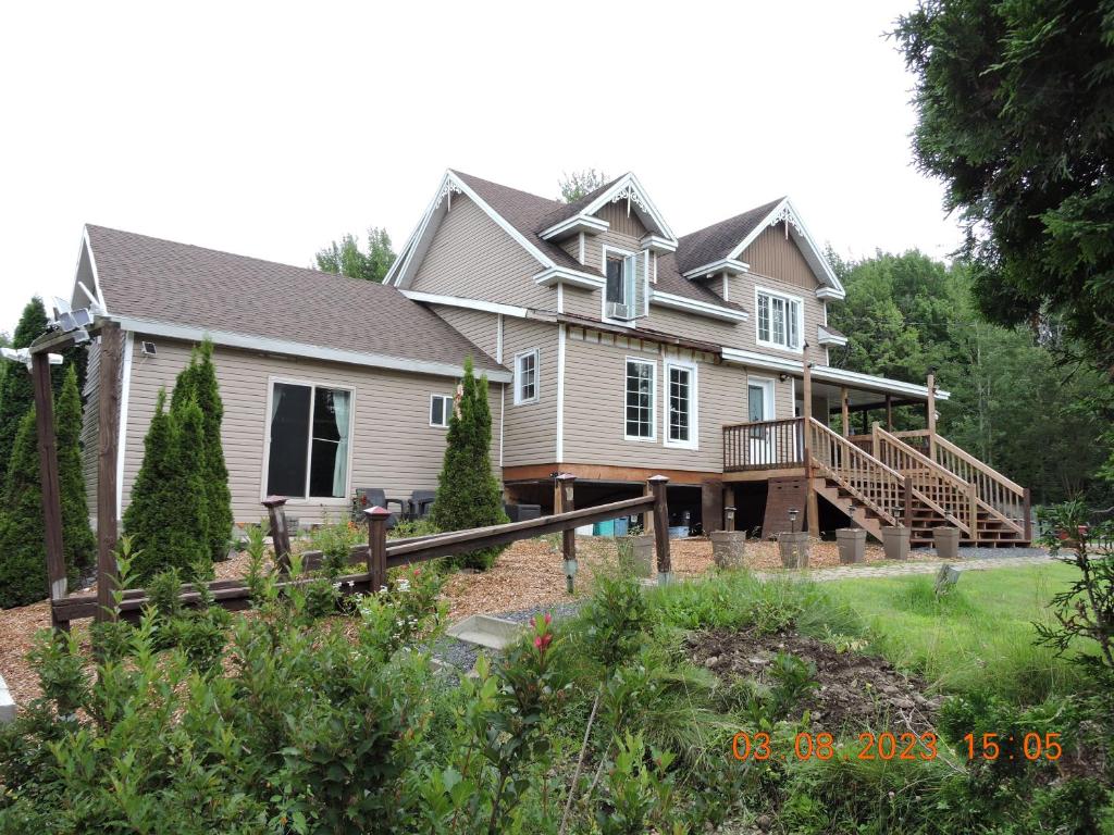 a large house with a porch and a deck at Gite Passion et Tendresse B&B in Shefford