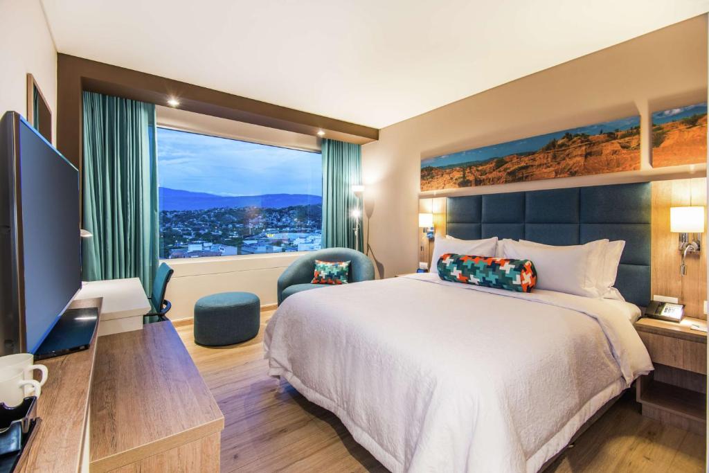 um quarto de hotel com uma cama e uma grande janela em Hampton By Hilton Cucuta em Cúcuta