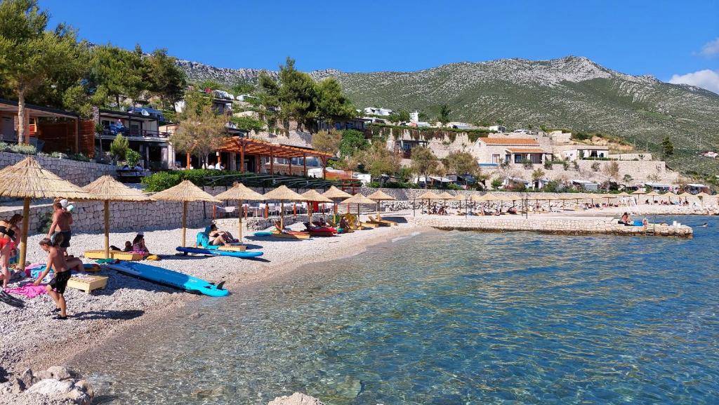 eine Gruppe von Menschen am Strand mit Sonnenschirmen in der Unterkunft Lavanda Mobile Homes & Villas in Orebić