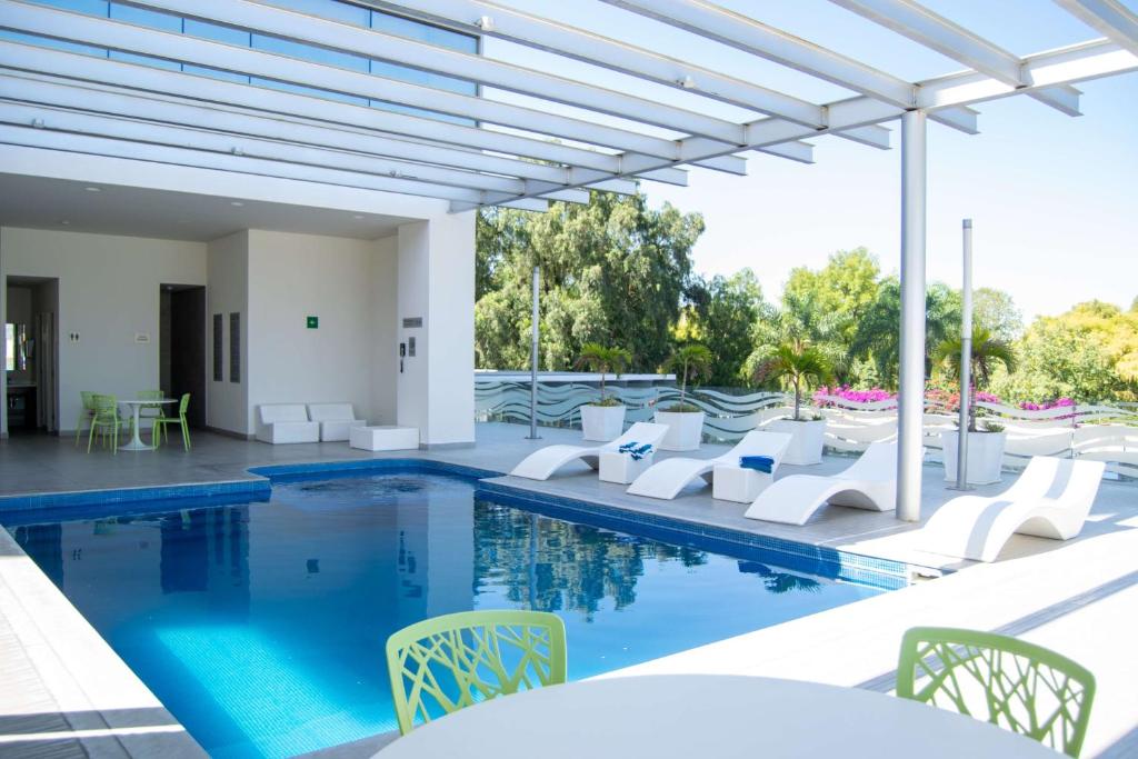 uma piscina com cadeiras e mesas brancas e uma piscina em Hilton Garden Inn Leon Poliforum em León