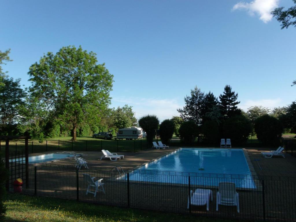 a swimming pool with chairs and a fence around it at Camping de la Croix d'Arles in Bourg