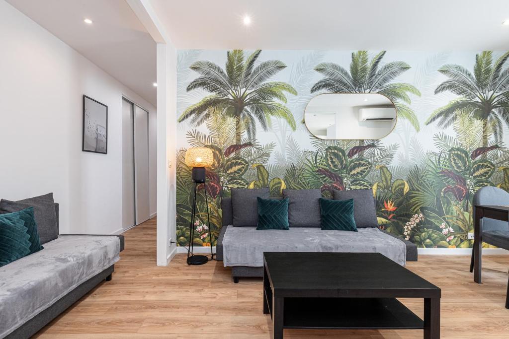 - un salon avec un canapé et une fresque murale de palmiers dans l'établissement LA CASA REINE JEANNE- CENTRAL prés de la gare - WIFI - PARKING - Neuf ET CONFORT, à Nice