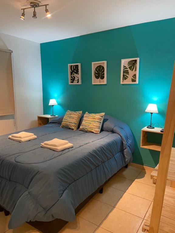 1 dormitorio azul con 1 cama grande y 2 almohadas en Padre Vázquez Apartment en Maipú