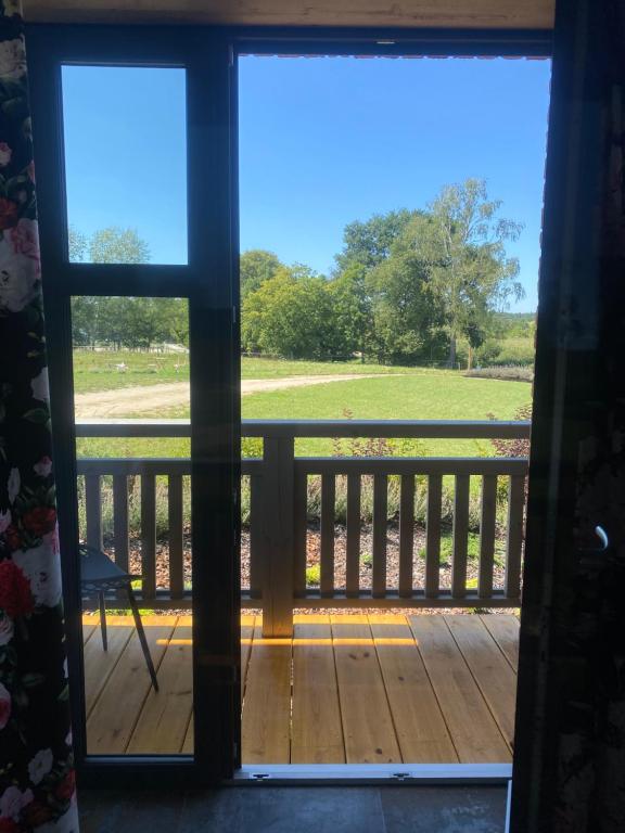 an open door to a deck with a view of a field at Lawendowy Domek in Ruciane-Nida