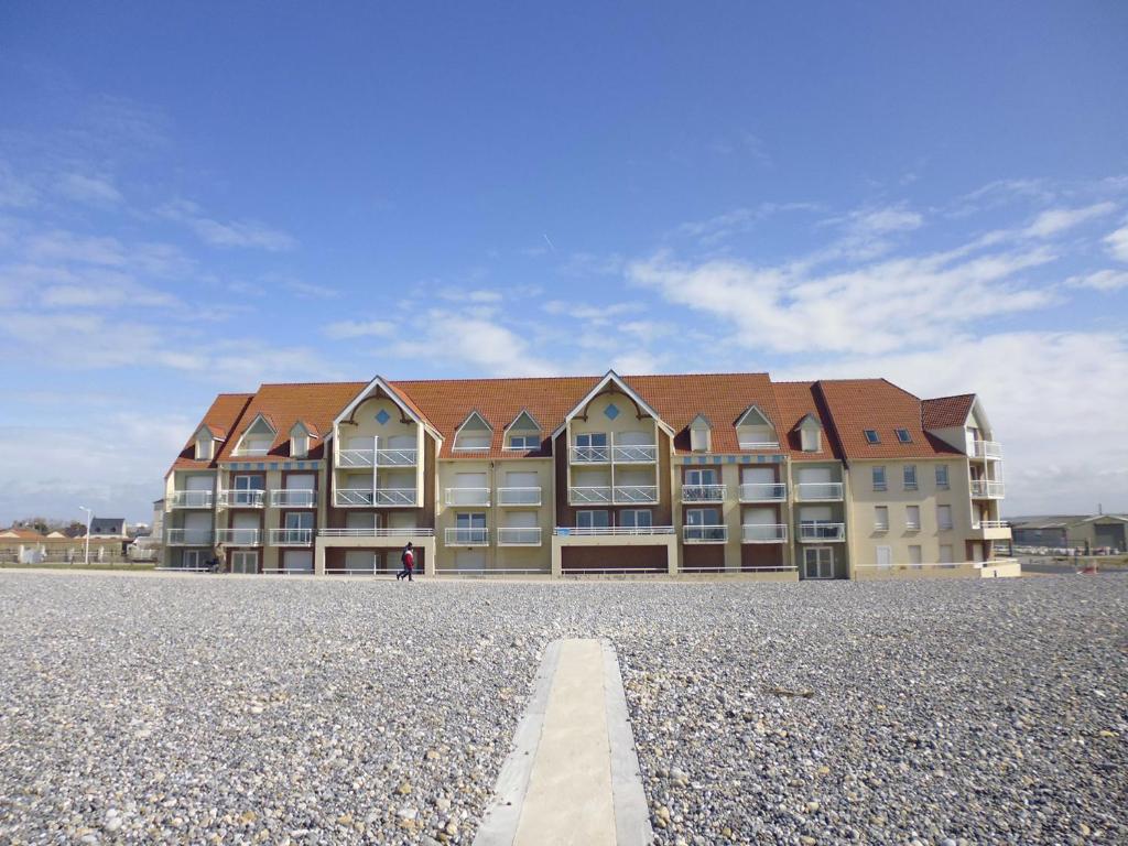 un grand immeuble d'appartements avec une route en face dans l'établissement Le Sémaphore, à Cayeux-sur-Mer