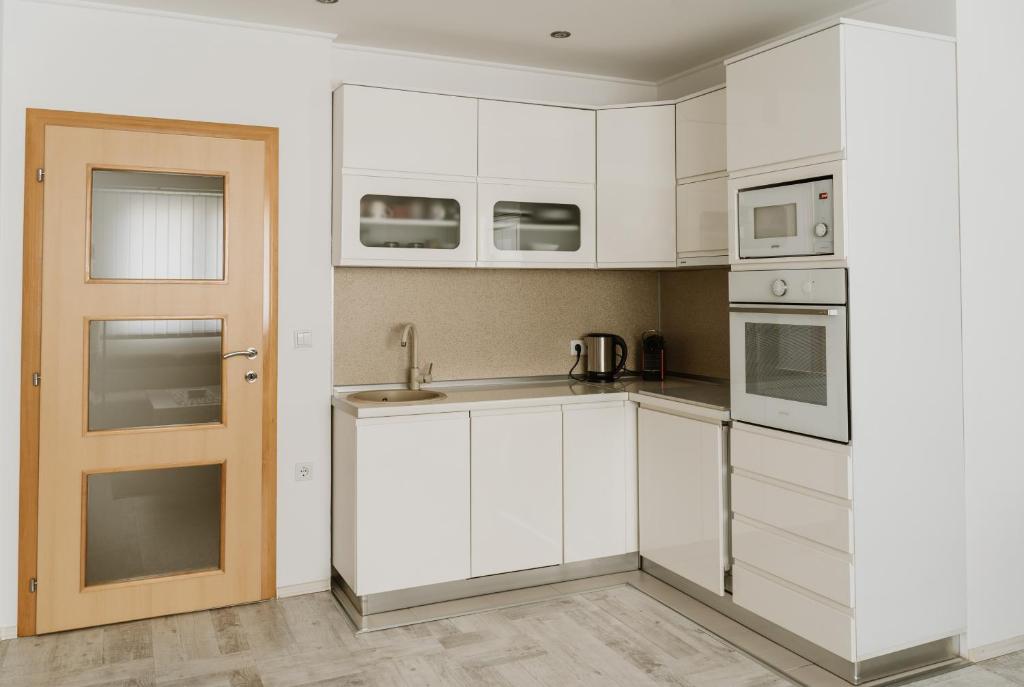 a white kitchen with white cabinets and a door at Apartman Stil in Bugojno