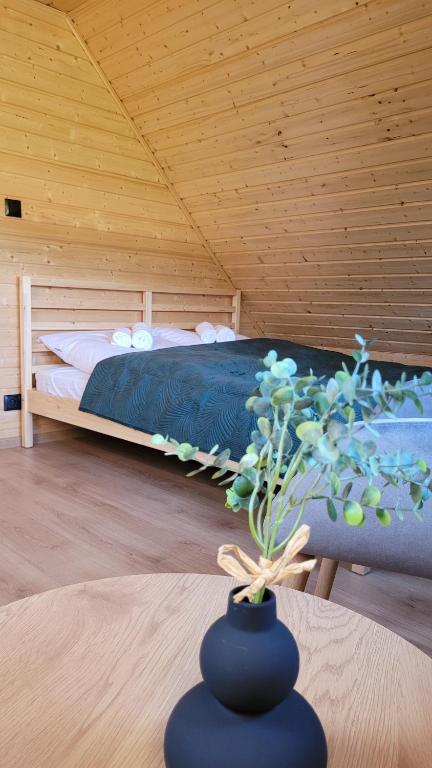 ein Schlafzimmer mit einem Bett und eine Vase mit einer Pflanze in der Unterkunft Sękowy Domek in Świeradów-Zdrój