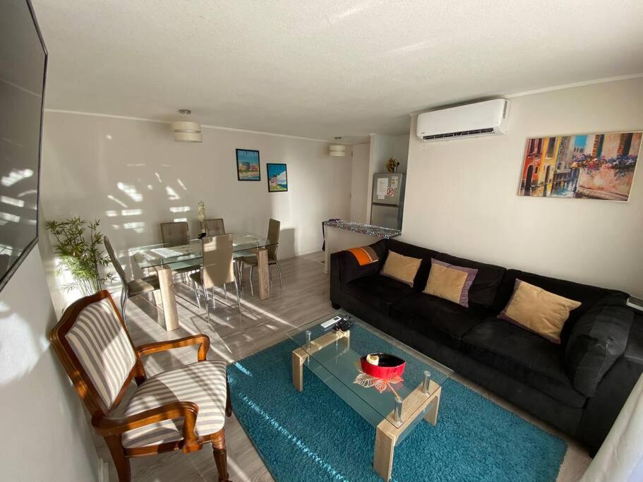 uma sala de estar com um sofá preto e uma mesa em Hermoso Departamento aire acondicionado, Internet em Talca