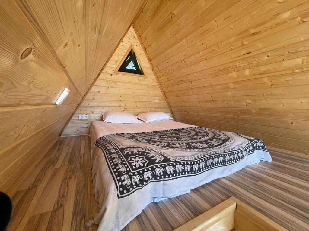 ein Schlafzimmer mit einem Bett in einer Holzhütte in der Unterkunft Eywa House in Kamenskoye Plato