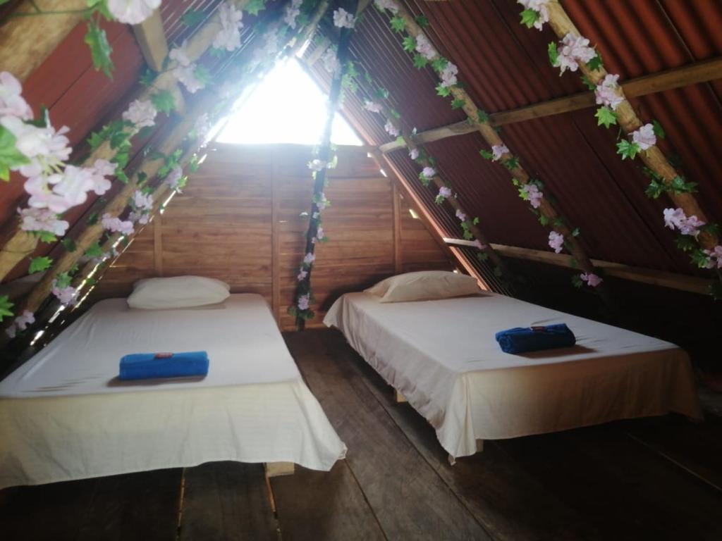 two beds in a room with flowers on the ceiling at Khalama in Baru