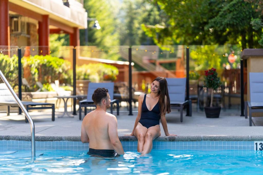 a man and a woman sitting in a swimming pool at Whistler Village Inn & Suites in Whistler
