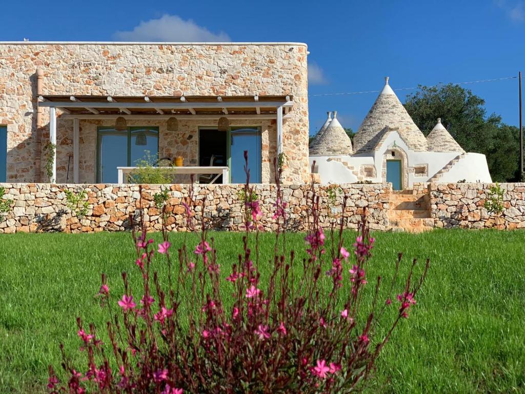 a stone house with pink flowers in the foreground at Trullo il Gatto Nero in Ostuni