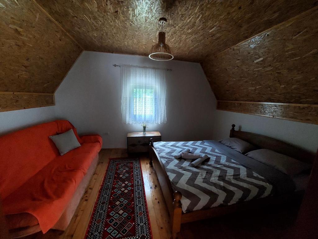 a bedroom with a bed and a couch and a window at Vila Paramida in Šavnik