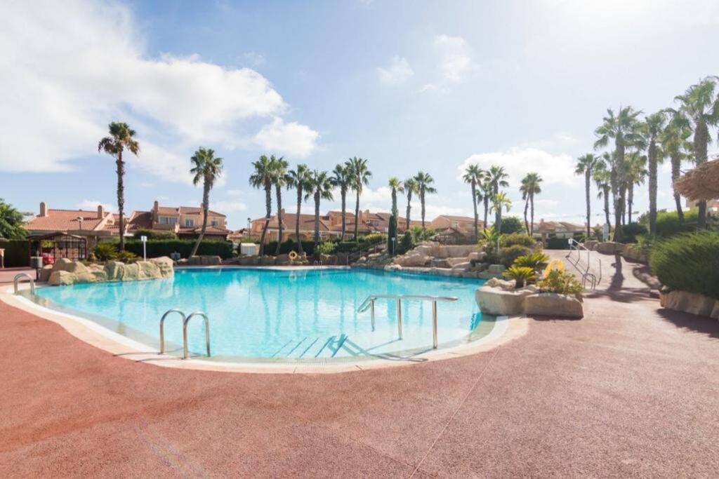uma grande piscina num resort com palmeiras em Casa Alanis em Gran Alacant
