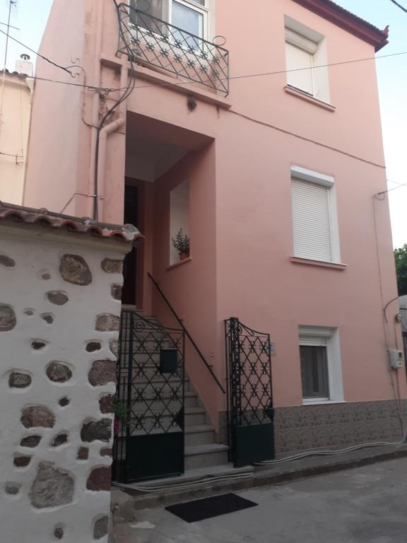 um edifício rosa com escadas e uma varanda em THALIA'S GARDEN em Mytilini