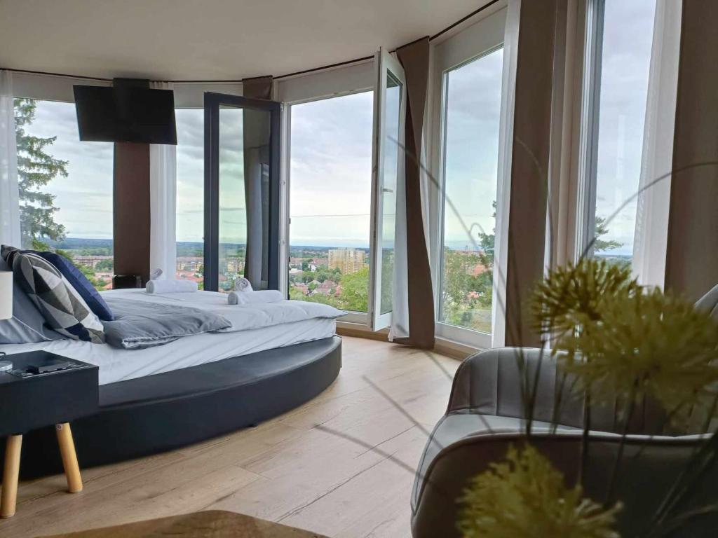 een slaapkamer met een groot bed en grote ramen bij WEST Panorama Penthouse - apartment with a fantastic view of the city in Szombathely