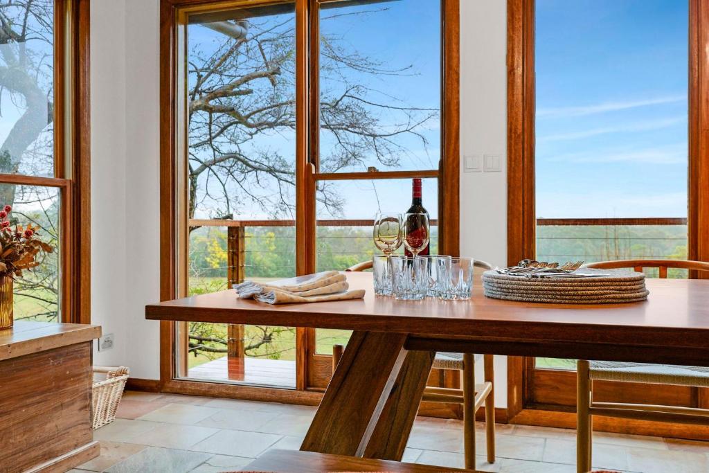 a dining room with a table with wine glasses at Christophers Cottage in Bilpin