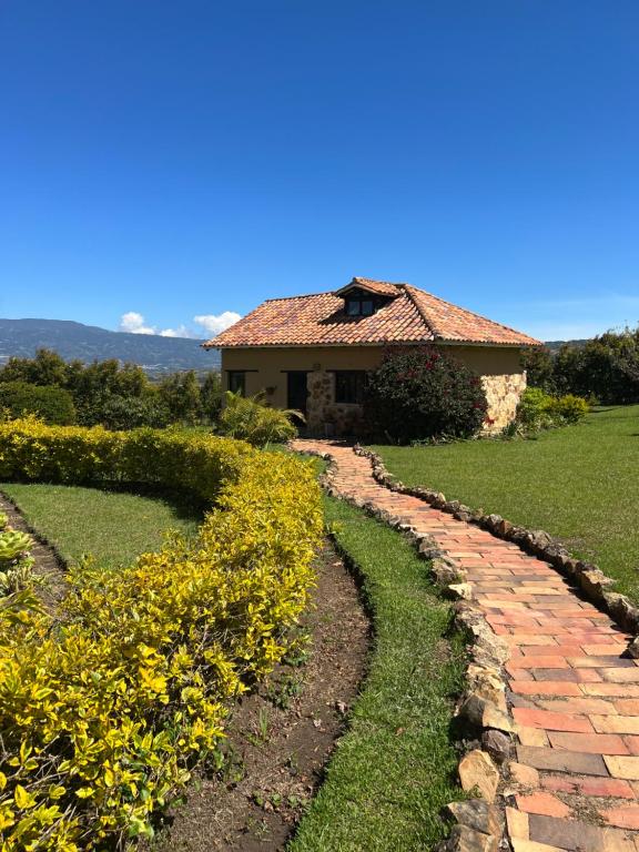 a brick path in front of a house with yellow flowers at Complejo turístico Magic Bungalow in Villa de Leyva