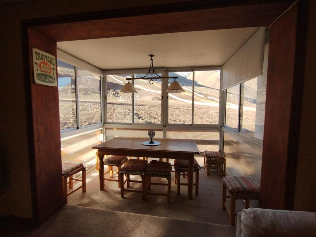Departamento Altos Penitentes Mendoza في لوس بينيتنتس: غرفة طعام مع طاولة وبعض النوافذ