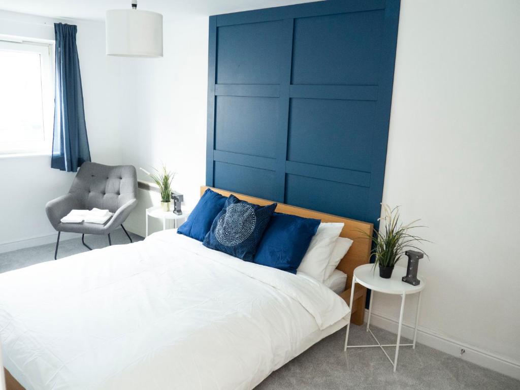 a bedroom with a large bed with a blue headboard at Stylish 2 bedroom apartment in the heart of Epsom town centre in Epsom