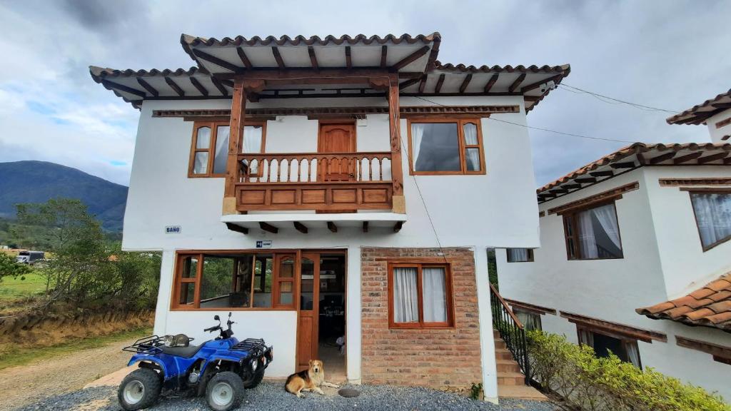 une maison avec un tracteur bleu garé devant elle dans l'établissement Caba-glamping La Fortuna de Luna, à Villa de Leyva