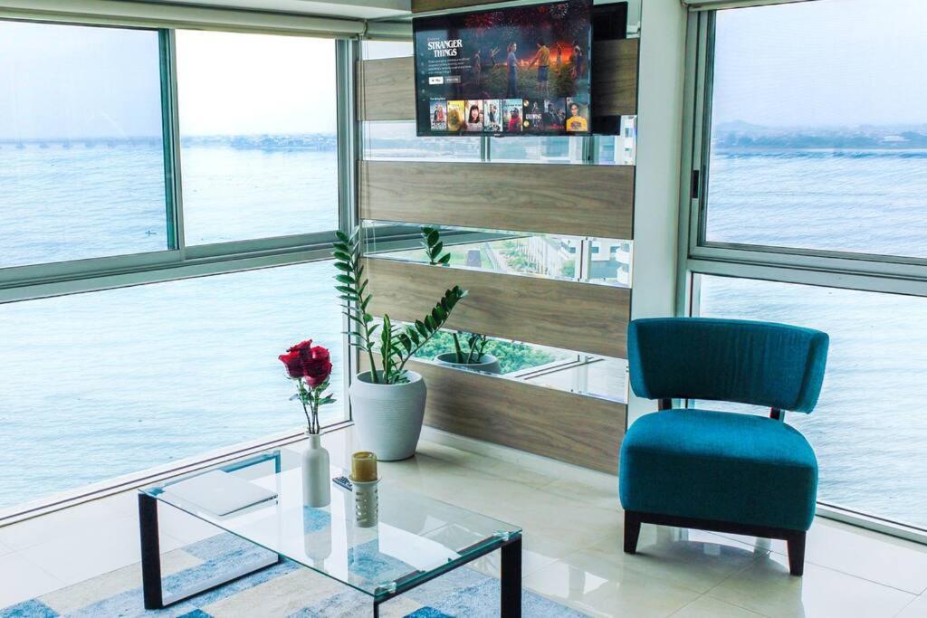 um quarto com uma cadeira azul e uma mesa de vidro em Suite 806 extraordinaria vista al rio con piscina. em Guayaquil