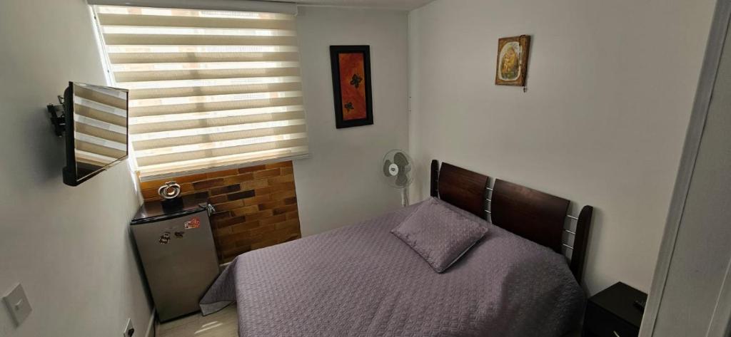 Un dormitorio con una cama con sábanas moradas y una ventana en APARTAESTUDIO EN VILLETA, en Villeta