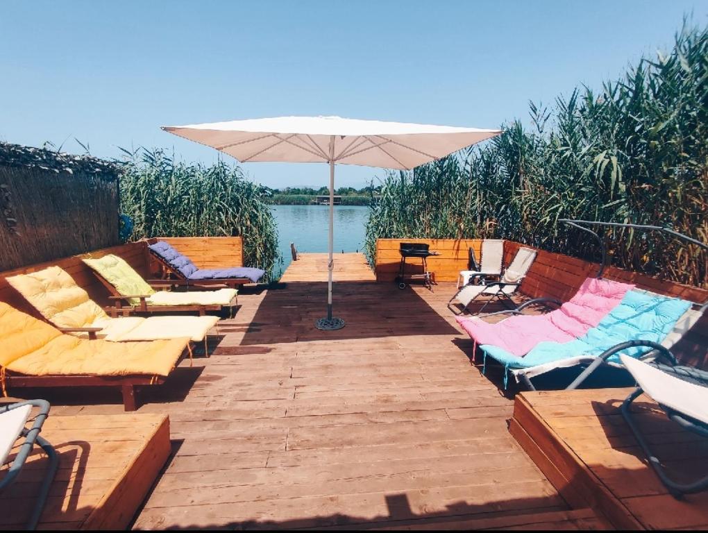 a wooden deck with chairs and an umbrella at Ada Bojana Green in Ulcinj