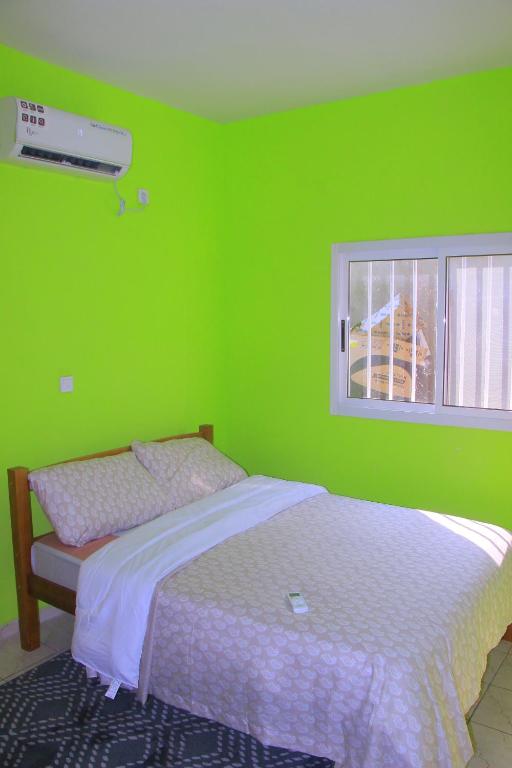zieloną sypialnię z łóżkiem i oknem w obiekcie Le beau séjour - Maison meublée 3 pièces w mieście Libreville