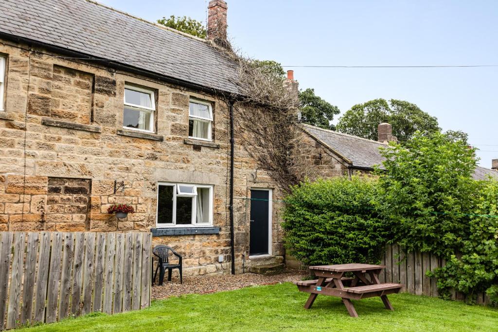 a picnic table in front of a stone cottage at Bilton Farm Cottage No2 in Alnmouth