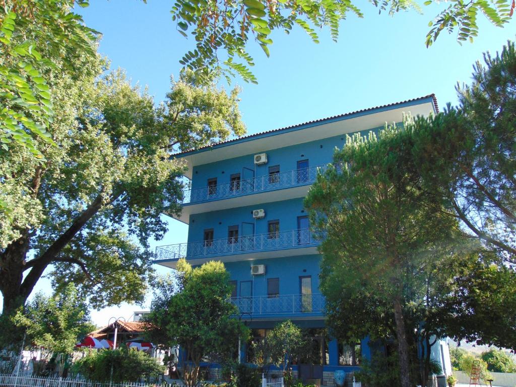 a blue building with trees in front of it at Hotel Mondo in Gjirokastër