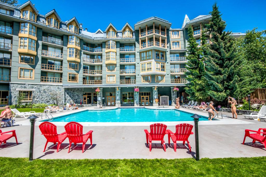 un gran edificio de apartamentos con piscina y sillas rojas en Cascade en Whistler