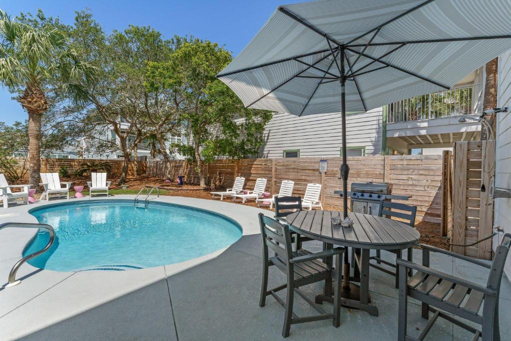 un patio con mesa y sombrilla junto a la piscina en Namaste Beaches S 11 84 Woodward St, en Destin