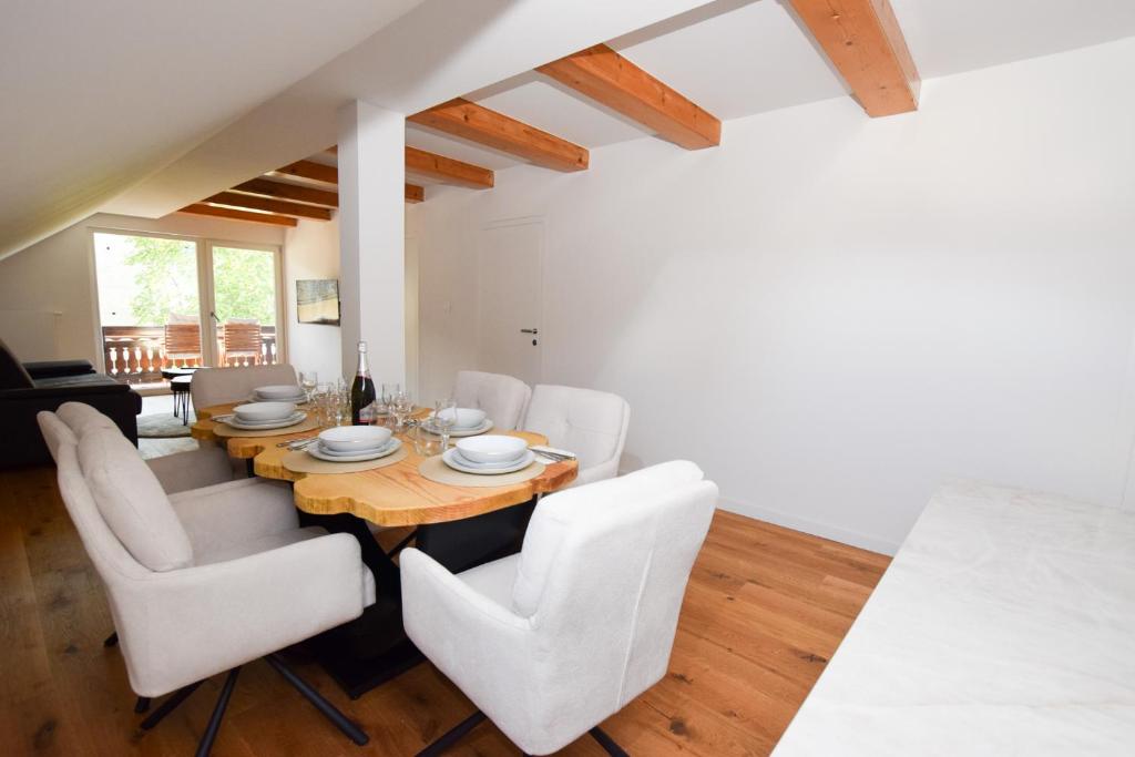 une salle à manger avec une table en bois et des chaises blanches dans l'établissement EROS APARTMENT Kranjska Gora, à Kranjska Gora