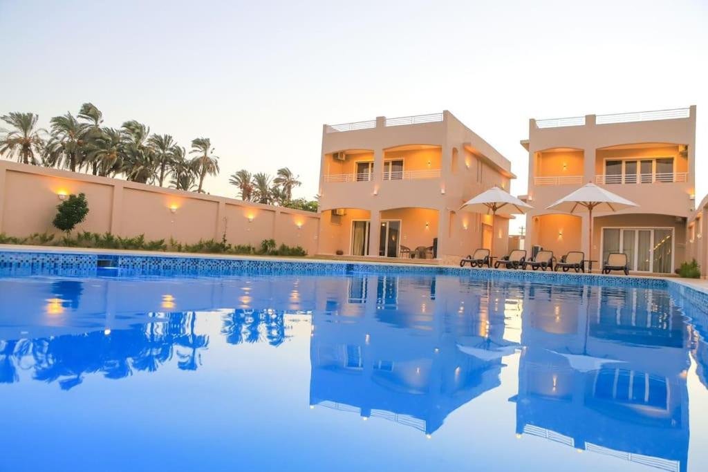 a large swimming pool in front of a house at Royal Nile Villas - Nile View Apartment 2 in Luxor