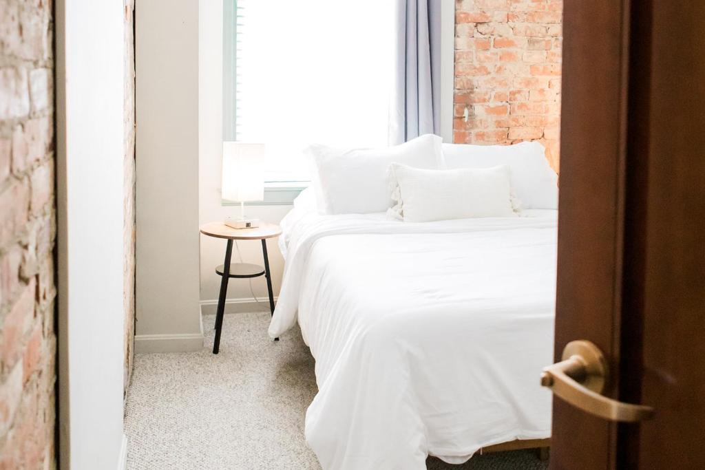 a bedroom with a bed with white sheets and a window at The Reserve - Heart of OTR 2 Bed Suite w/Views in Cincinnati