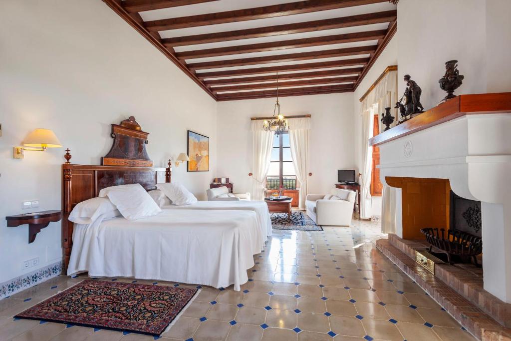 une chambre avec deux lits et une cheminée dans l'établissement Hotel Llenaire, à Port de Pollença