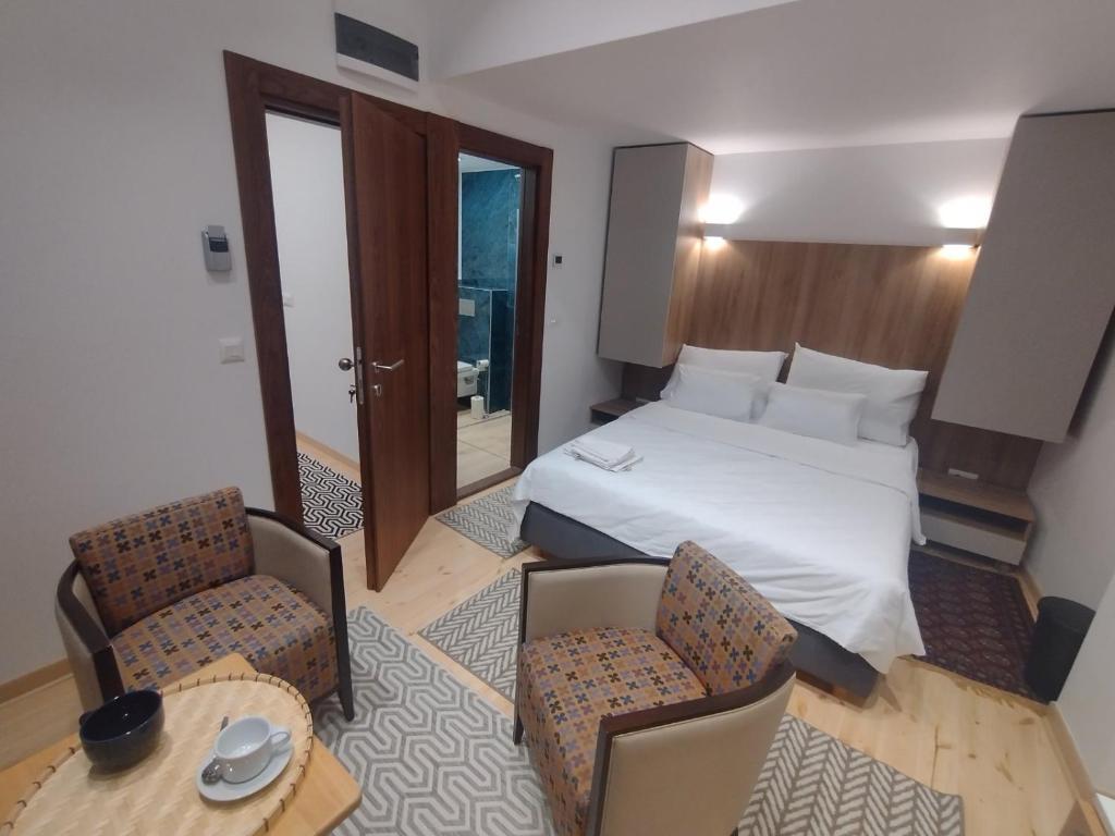 une chambre d'hôtel avec un lit, une table et des chaises dans l'établissement Balkanska Four Seasons Suites, à Belgrade
