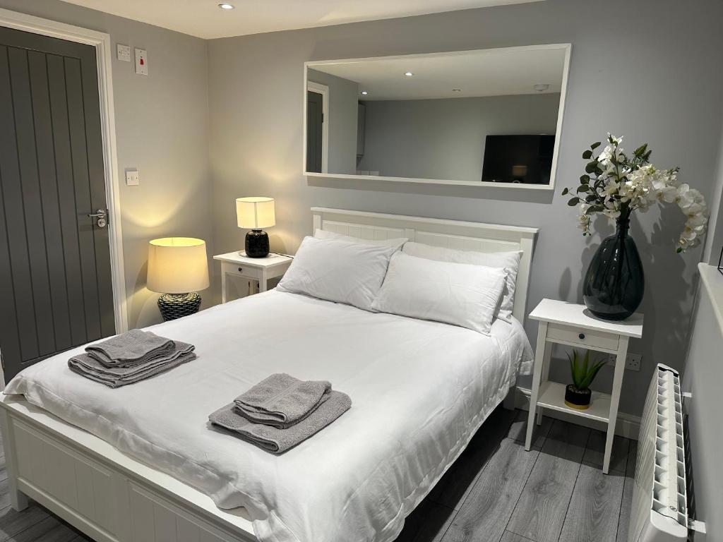 a bedroom with a white bed with towels on it at Modern Luxury Private Detached 1 Double Bedroom Studio Apartment - Super Fast Wifi in Luton