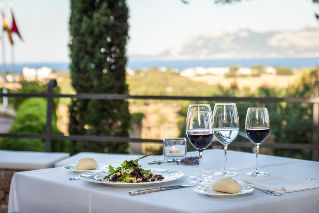 - une table avec des verres à vin et une assiette de nourriture dans l'établissement Hotel Llenaire, à Port de Pollença