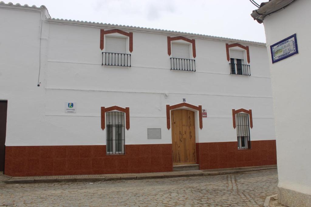 un edificio blanco con puerta y ventanas de madera en Casa Rural El Nini, 