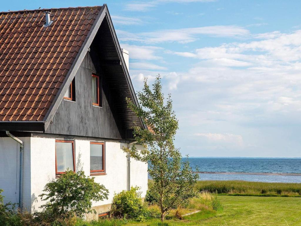 una casa bianca con un tetto nero vicino all'oceano di Holiday home Assens IX ad Assens
