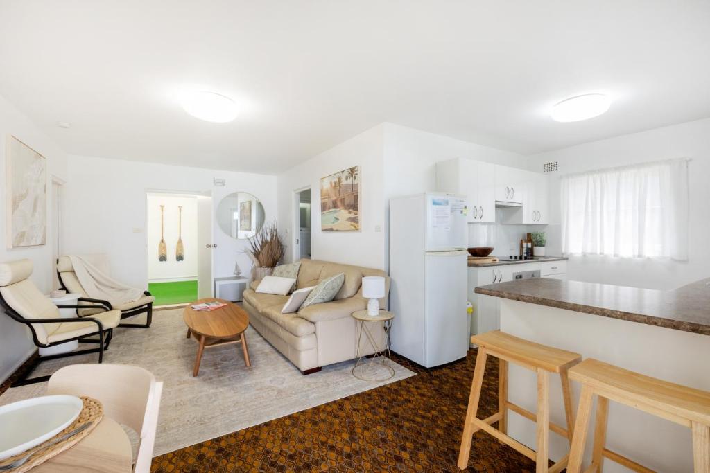 a living room with a couch and a kitchen at Beach View Mollymook in Mollymook